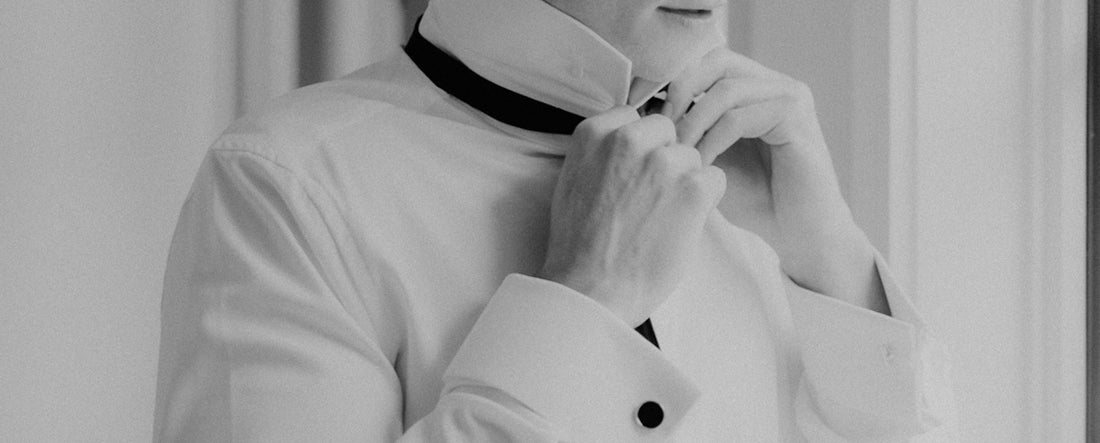 a black and white photo of a woman adjusting her collar